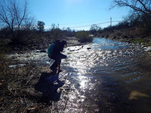 Student walking through flowing Tucson River