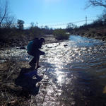 Student walking through a flowing Tucson River
