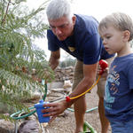 Tucsonan Scott Mencke, and his 3-year-old son, Reef, use water from their water havesting cistern to water their garden at home. 